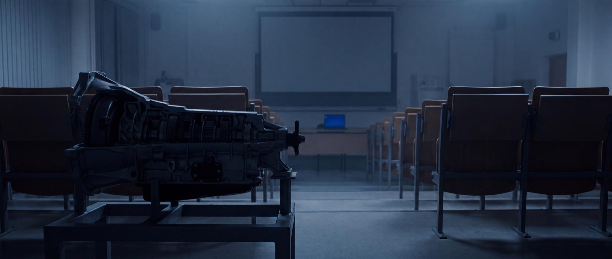 Illustrative: an empty technical training room at dawn with a cutaway drivetrain on a stand